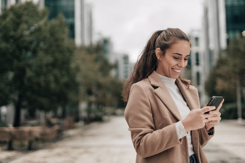 Mulher segurando o celular e pesquisando como emitir a segunda via SAAE
