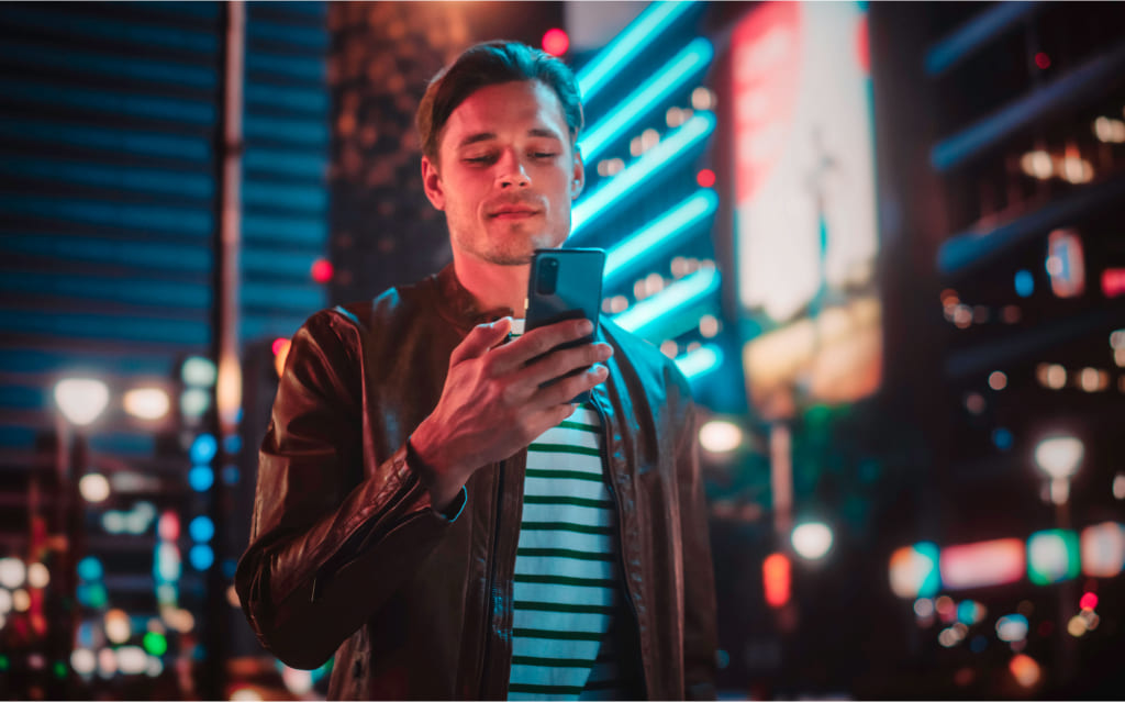 homem branco sorri enquanto olha para o celular e pensa em qual a importância da nota de corretagem