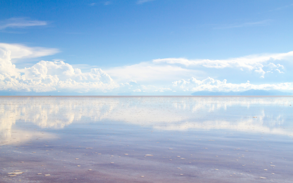 Paisagem deslumbrante de um lago com reflexos de nuvens no céu azul, criando uma atmosfera tranquila e serena. Ideal para contemplação e fotografia.