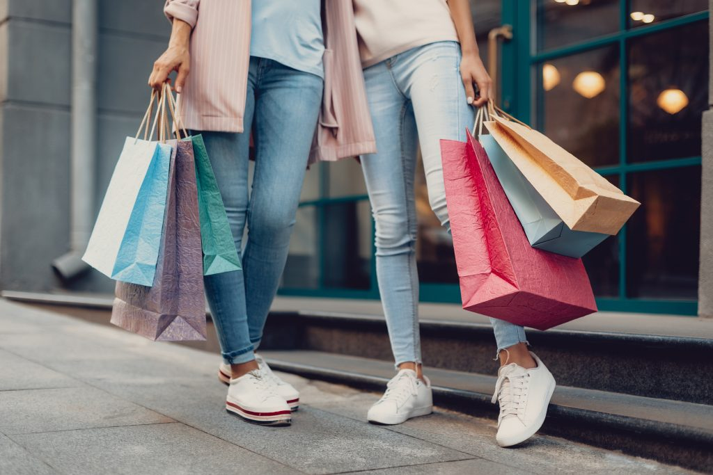 Duas pessoas segurando sacolas de compras, aparecendo da cintura para baixo