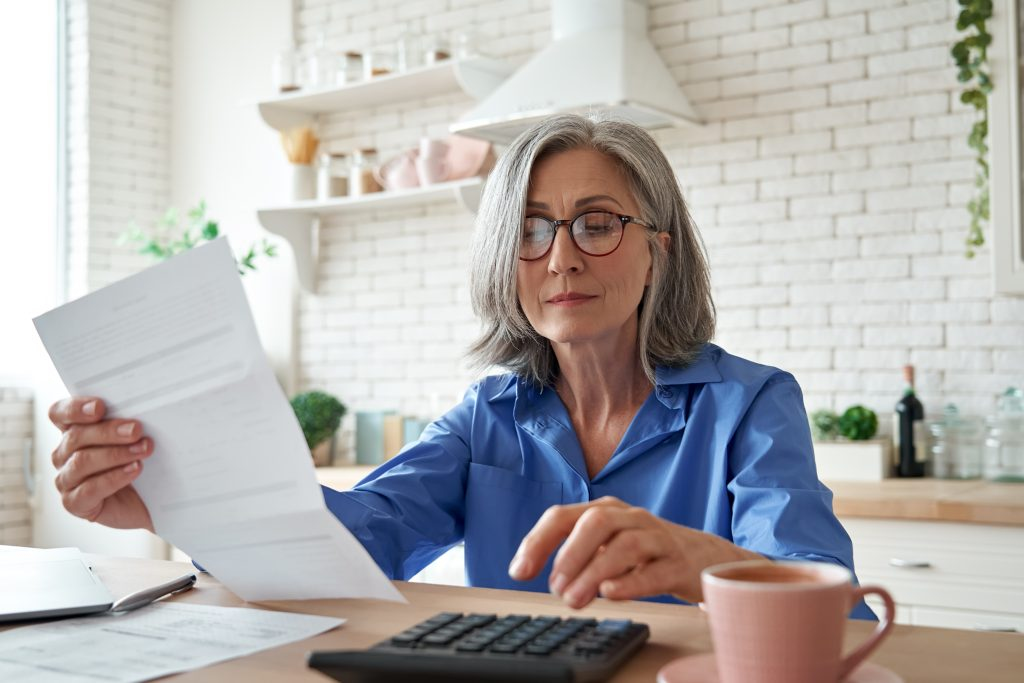 Mulher segurando um papel e com uma calculadora, pensando em como declarar PGBL no IR 2022