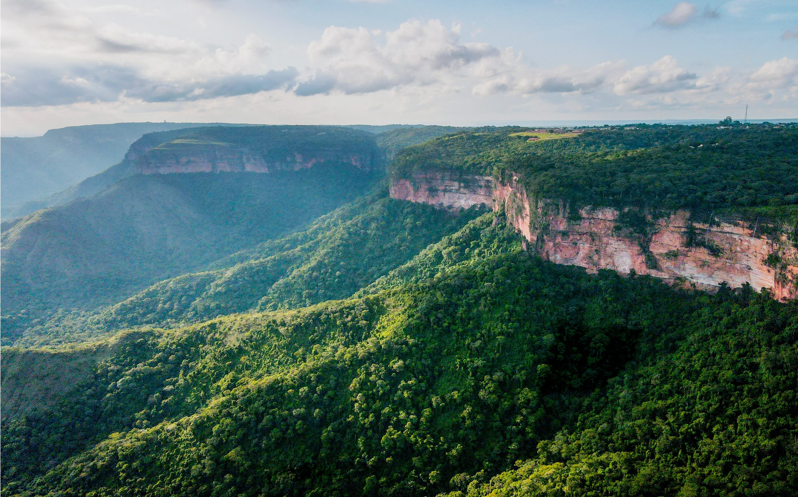 Vista panorâmica de um deslumbrante cânion rodeado pela vegetação exuberante das montanhas, mostrando a beleza natural da região.