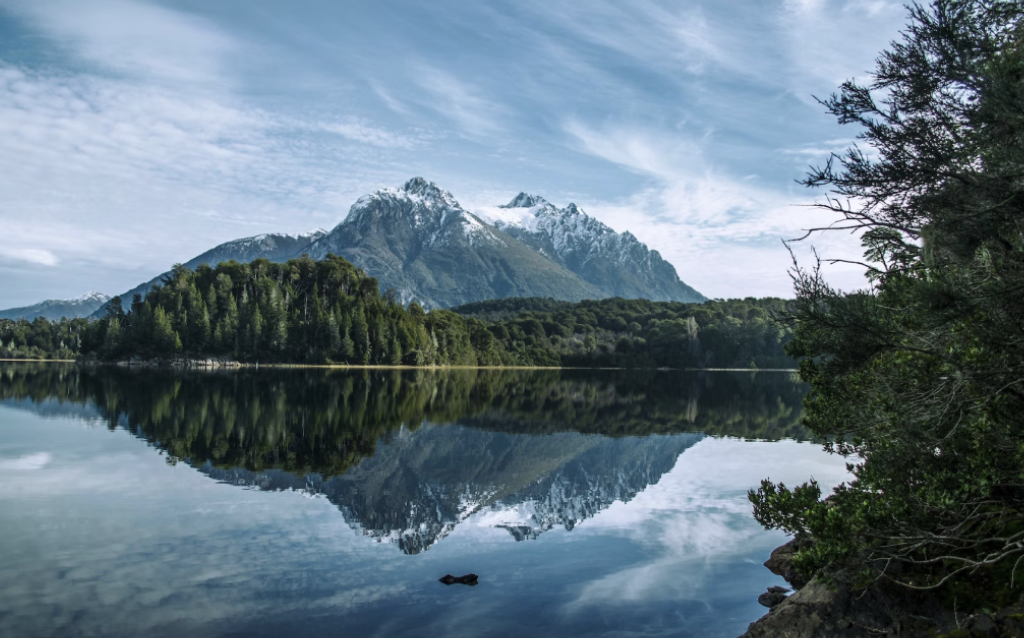 Montanhas de Bariloche atrás de uma floresta de árvores e de um lago
