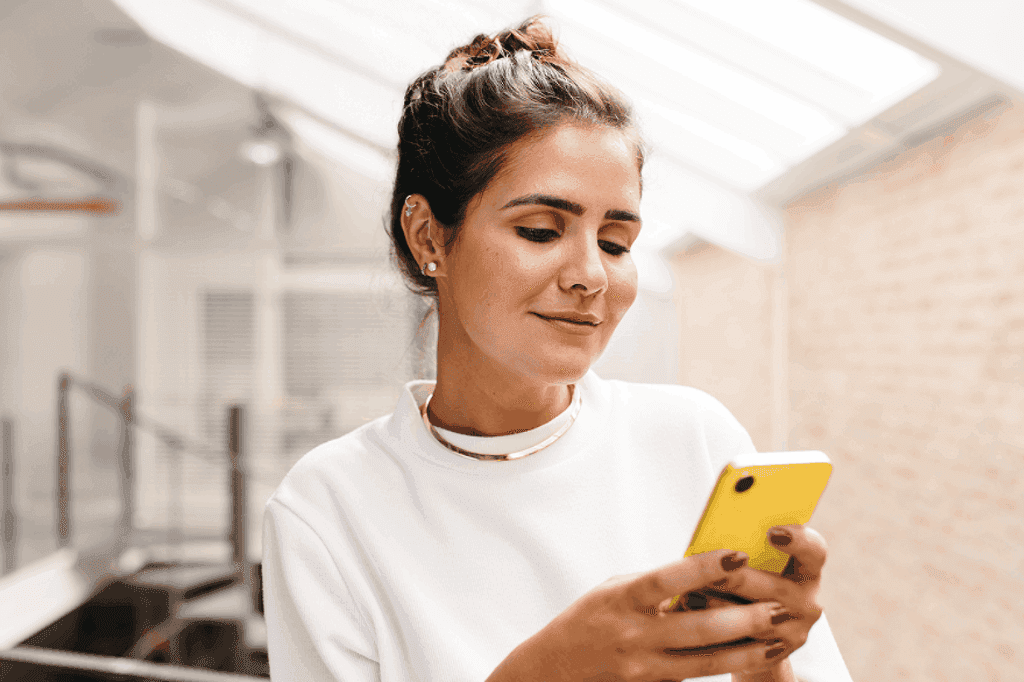 Pessoa mexendo no celular, representando uma decisão entre banco ou corretora.