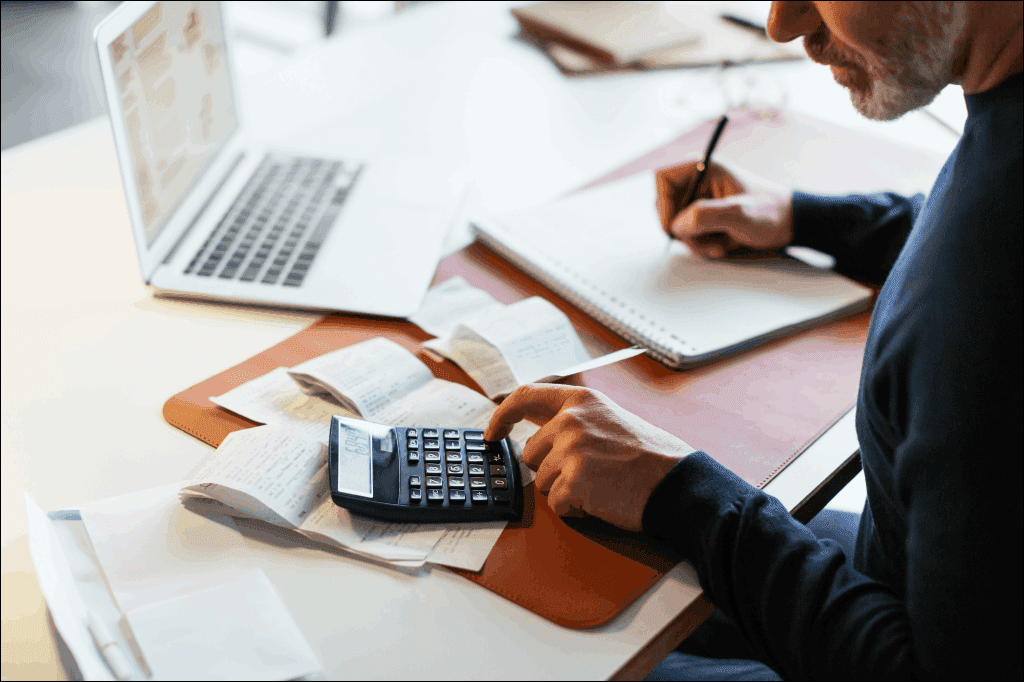 Empreendedor usando a calculadora e fazendo anotações sobre o caixa de sua empresa
