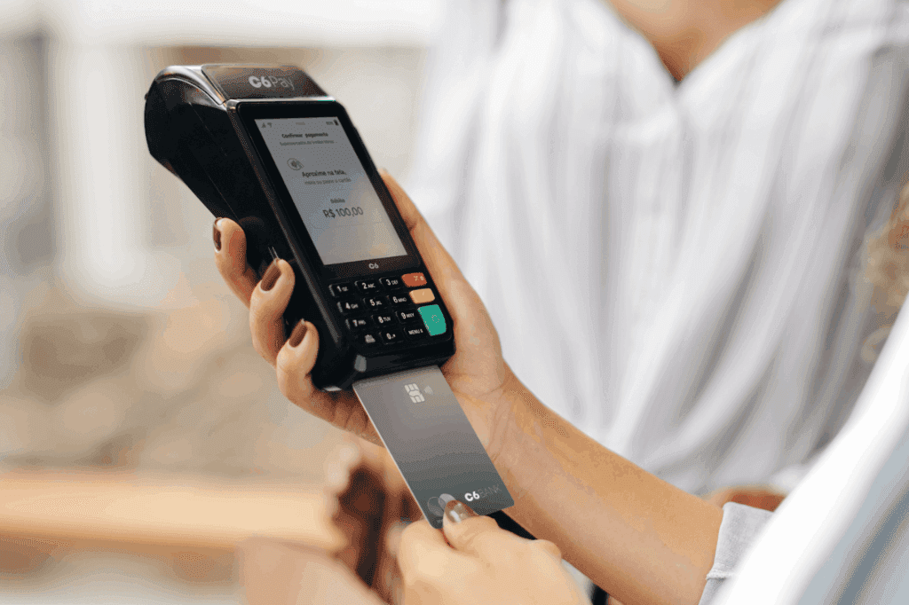 Empresário passando uma compra em sua maquininha C6 Pay, representando o impacto da mudança da DIRF