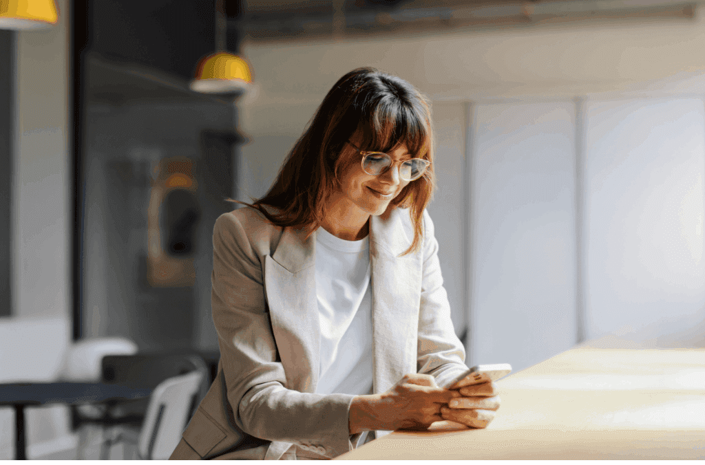 mulher empreendedora de terno e mexendo no celular, representando um empréstimo consignado MEI