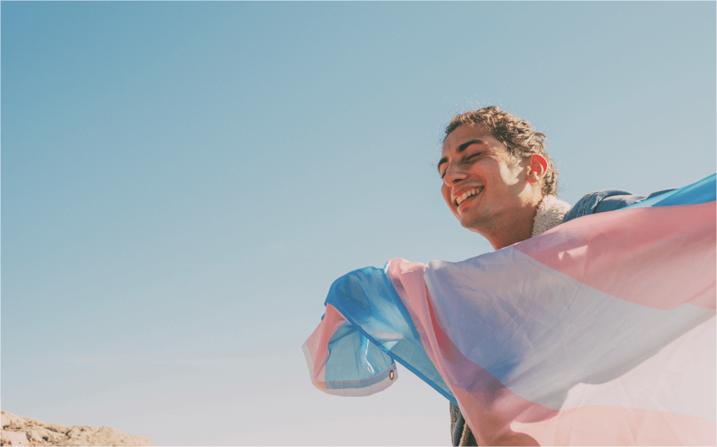 Pessoa com a bandeira trans, simbolizando inclusão e orgulho com o uso do nome social.