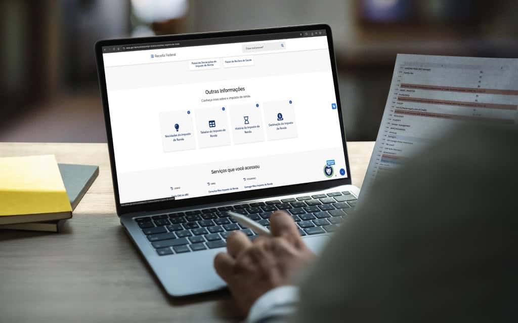 Pessoa acessando o site da Receita Federal no notebook para consultar informações sobre o Imposto de Renda.