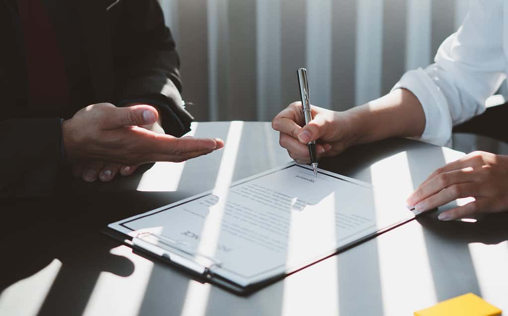 Pessoa assinando contrato de trabalho em mesa de escritório, representando o conceito de salário bruto antes dos descontos.