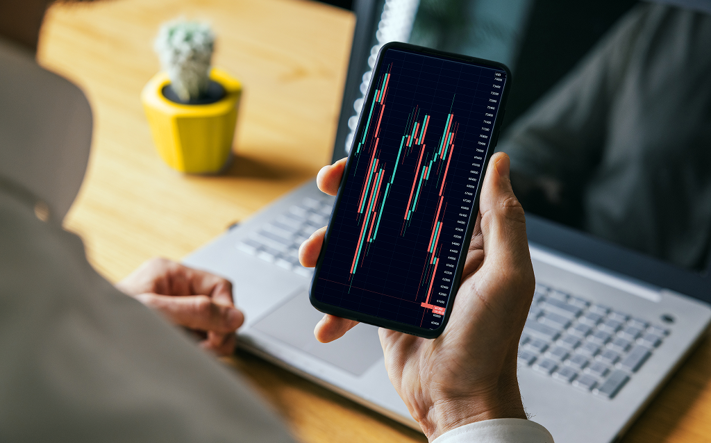 Pessoa segurando um celular com um gráfico volátil