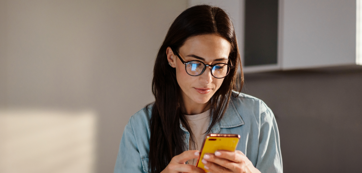 Mulher de óculos olhando smartphone em suas mãos