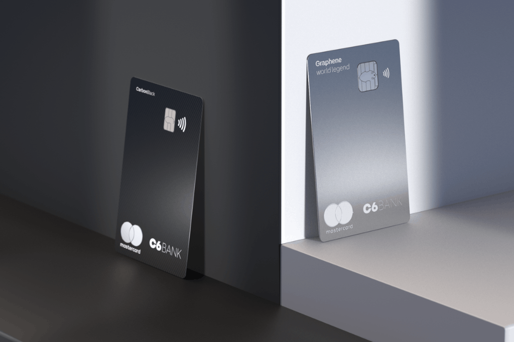 Cartão C6 Carbon ao lado do cartão C6 Graphene, mostrando bem seus detalhes e diferenças. Ambos estão de pé, apoiados.