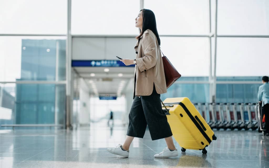 Mulher andando com uma mala amarela pelo aeroporto