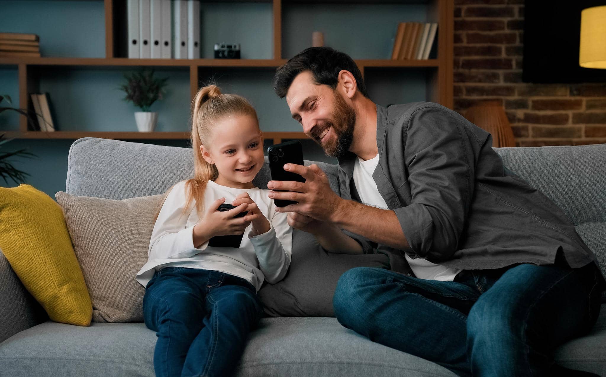 Pai mostrando para filha as funcionalidades do cartão de débito infantil.