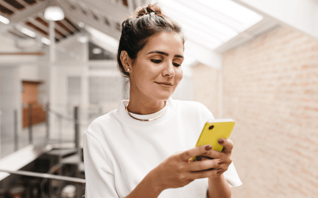 Mulher no celular utilizando a funcionalidade Click to Pay em lojas online