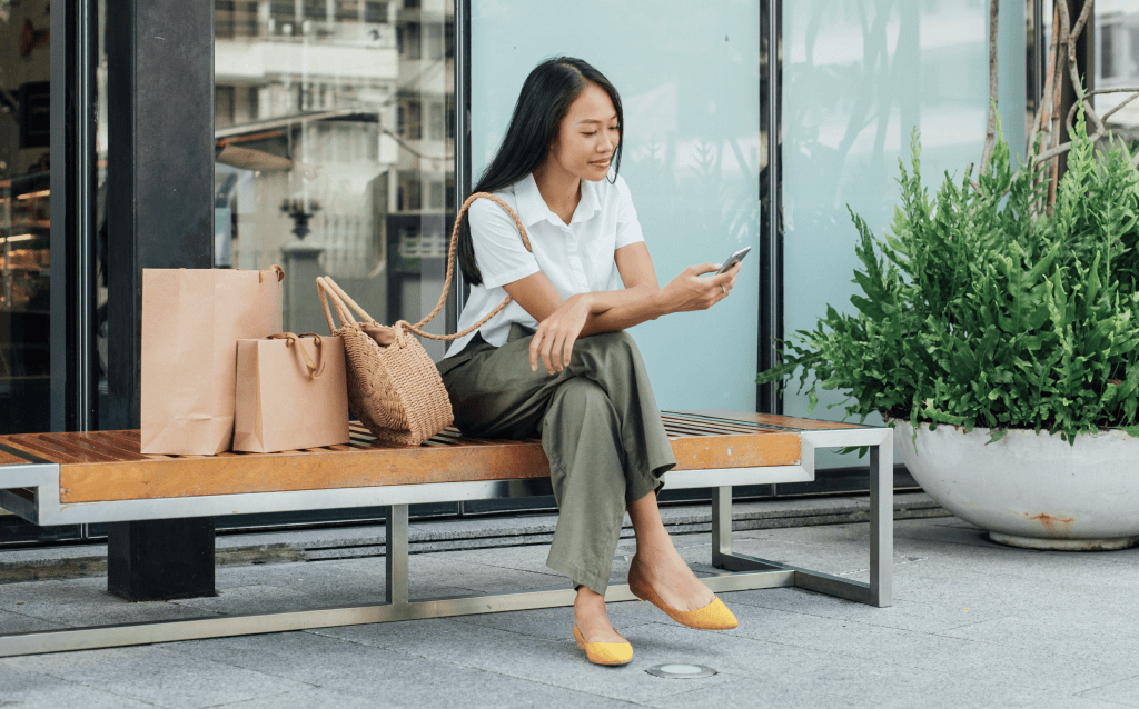 Mulher com compras checando app do banco no celular