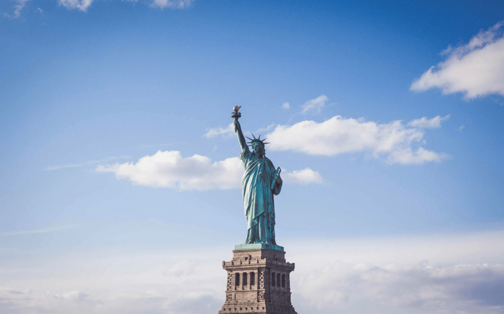 Centralizada na imagem está a Estátua da Liberdade com o céu nublado como fundo.