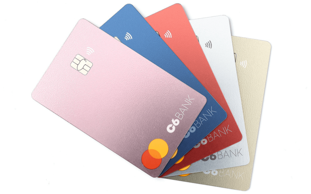 5 cartões standard do C6 Bank, nas cores rosa, azul, vermelho, branco e dourado.
