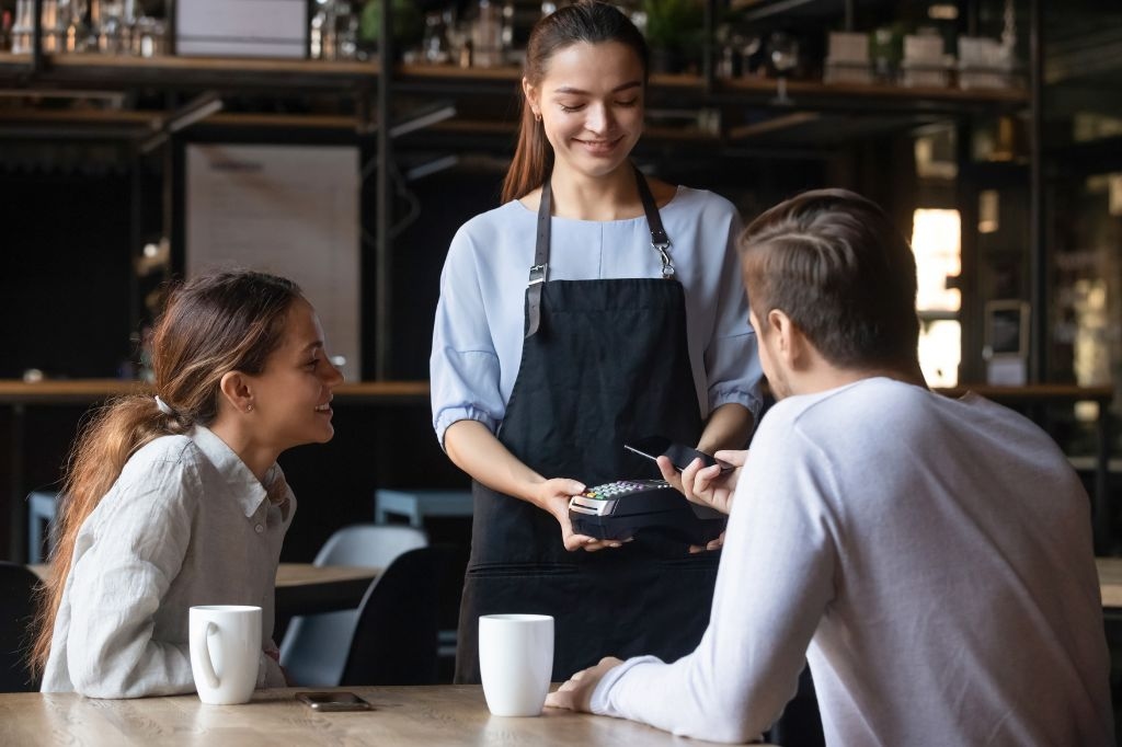 como nfc funciona - casal fazendo pagamento por aproximação com celular em um comércio