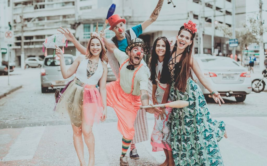 feriados facultativo | grupo de amigos composto por dois homens e duas mulheres em diferentes fantasias no carnaval, uma das mulheres tem cabelo longos e loiros e está vestida de unicórnio, os dois homens vestem roupas de palhaço e estão com os rostos pintados, e as outras duas moças estão com vestidos e elementos de carnaval