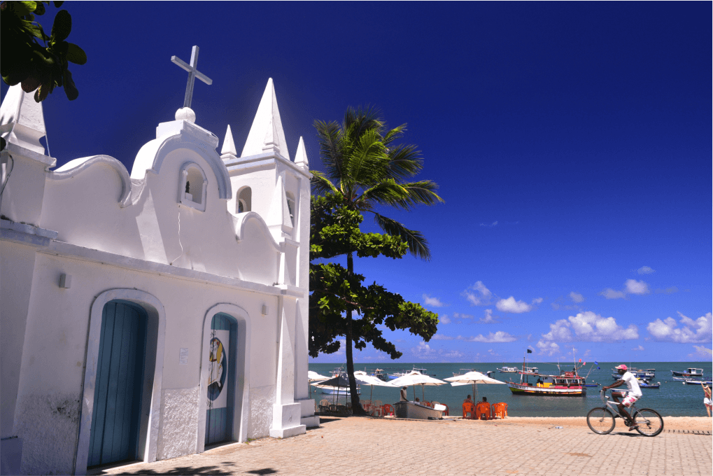 Foto de uma capela na areia com o mar ao fundo na Praia do Forte.
