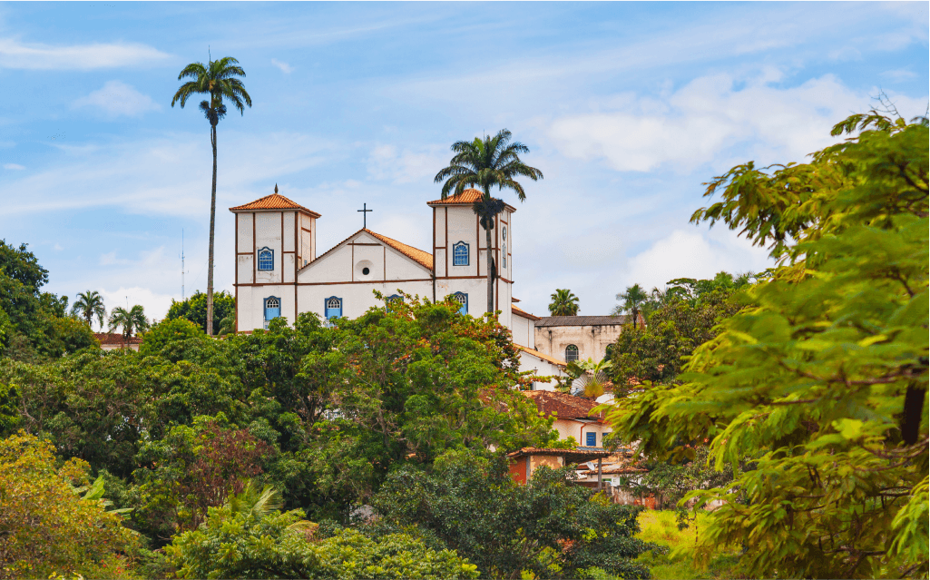 Imagem de copas de árvore cercando uma igreja tradicioanal em Pirenópolis.