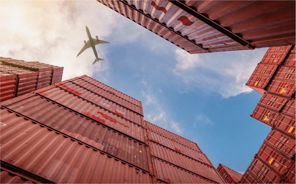 Imagem de um avião passando por cima de diversos container. câmbio pronto