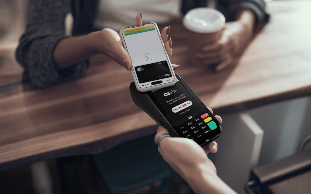 Imagem de uma maquininha do cartão de crédito passando o pagamento por aproximação pelo celular. como funciona o chip do cartão de crédito