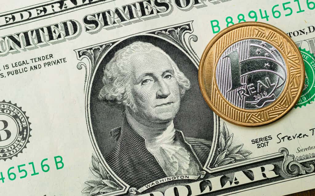 Imagem mostrando dólar americano e uma moeda de um real