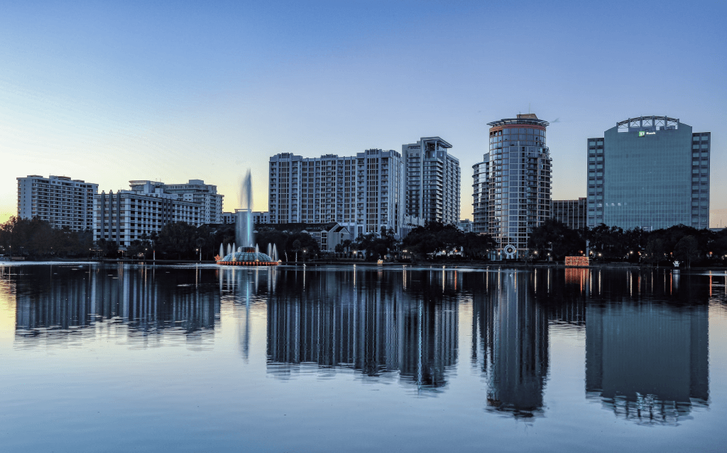 Lago localizado no meio da cidade, cercado de prédios que tem suas imagens refletidas na água.