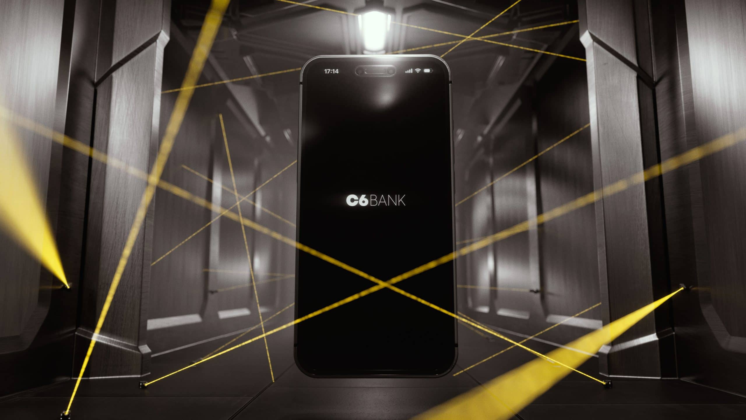 Uma imagem mostra um celular em um corredor protegido por lasers amarelos. Na tela do celular, está o logo do C6 Bank em um fundo preto. As paredes do corredor são cinzas.