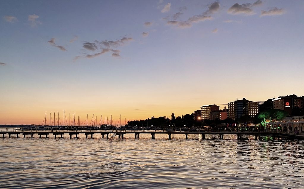 portoroz praia com céu na tonalidade degrade pôr do sol, píer e prédios