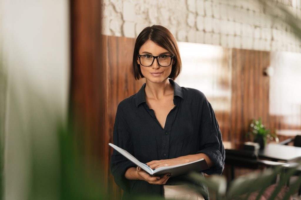 Mulher em pé segurando um caderno