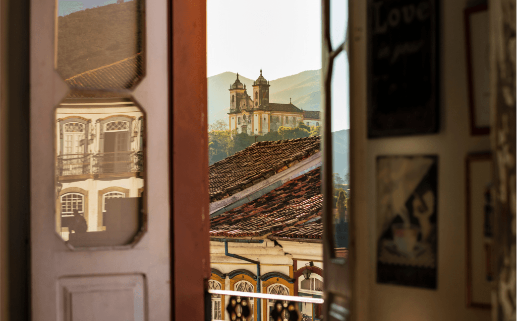 Uma igreja histórica vista pela fresta de uma janela colonial.