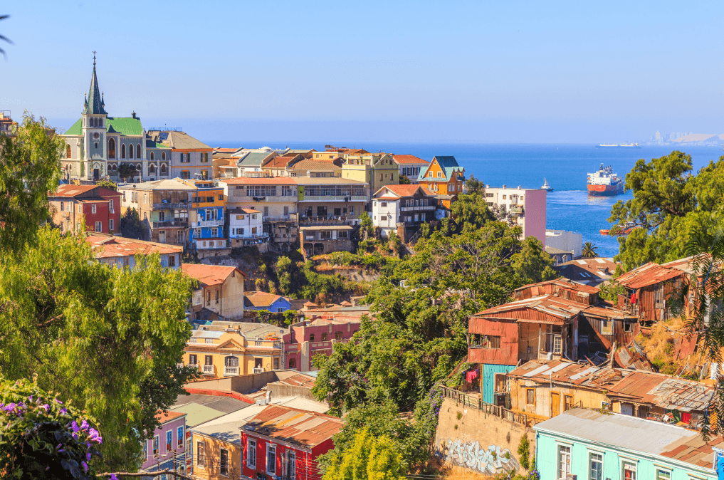 Várias construções tradicionais e coloridas de Valparaíso com o mar ao fundo.