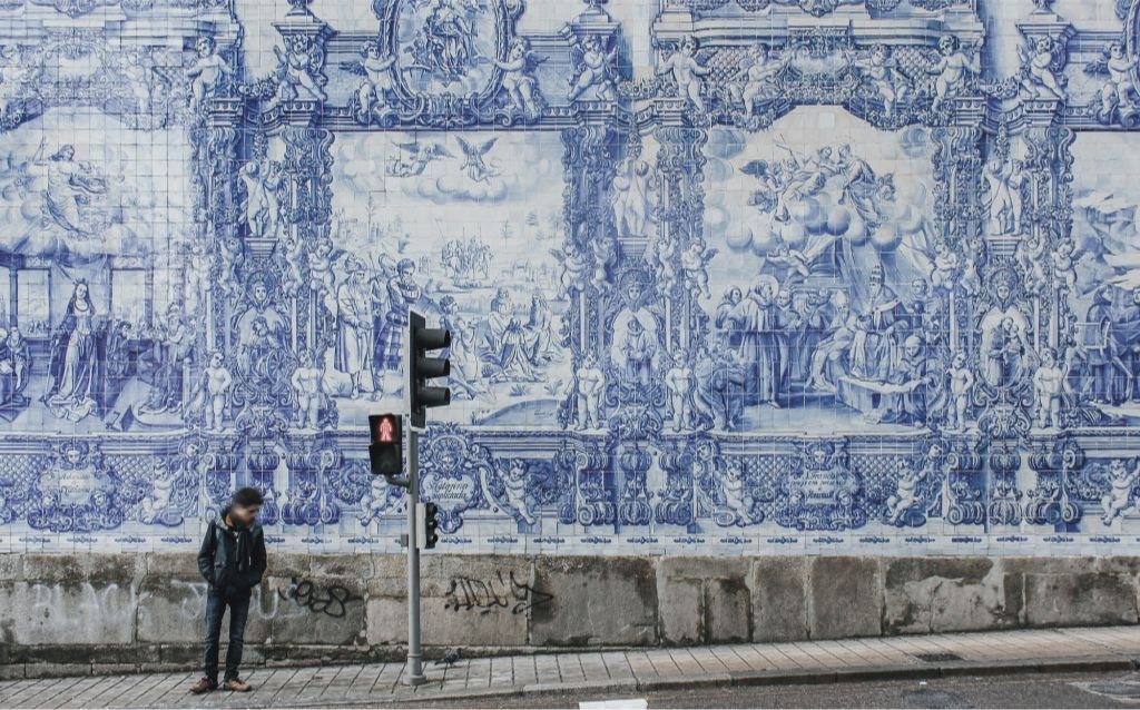 viagem feriado prolongado - Portugal - painel com típica azulejaria portuguesa com uma pessoa parada ao lado de um semáforo