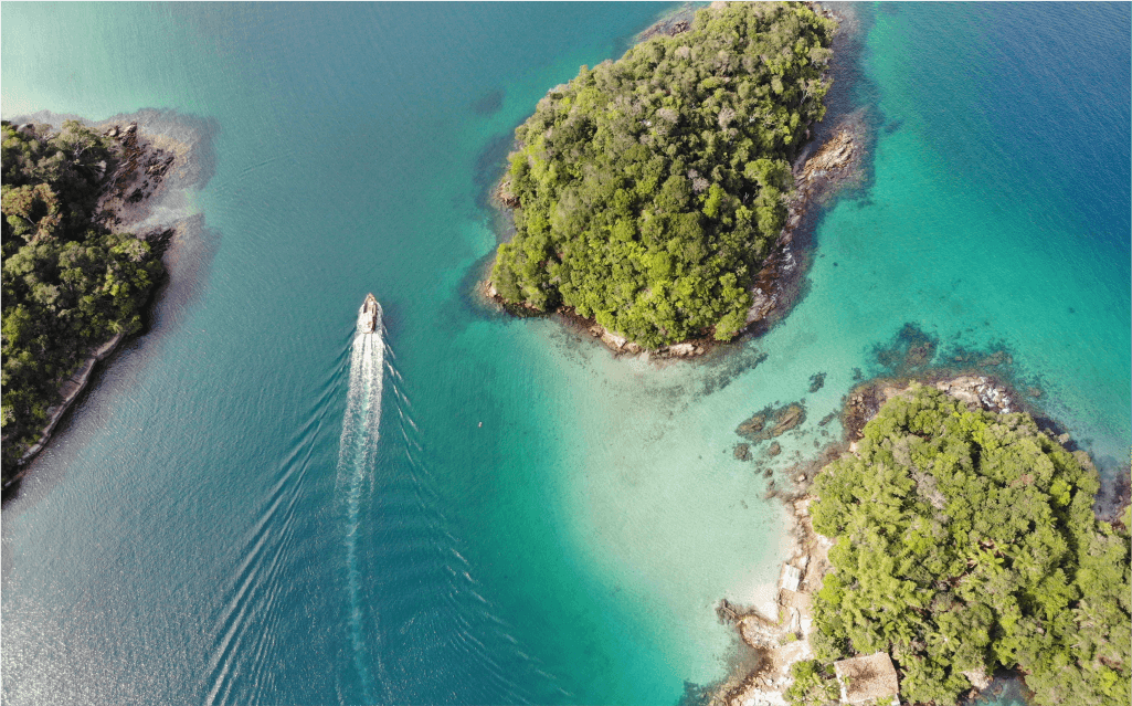 Vista de cima de uma bahia de água salgada com montes verdes em ao redor de um barco na Ilha Grande.