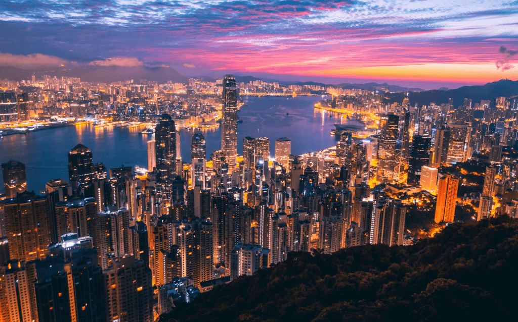 Vista panorâmica da cidade durante a noite, com todos os prédios iluminados e com um grande rio no meio.