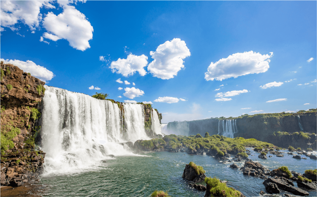 Vista panorâmica de uma das cahoeiras de Foz do Iguaçu em um dia ensolarado e com céu azul.