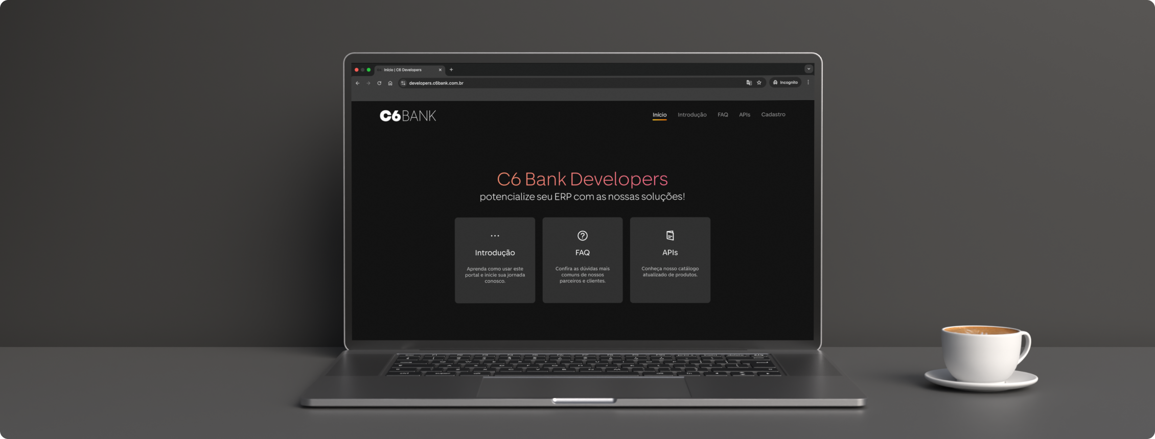 Notebook com site C6 Bank Developers aberto ao lado de uma xícara de café.