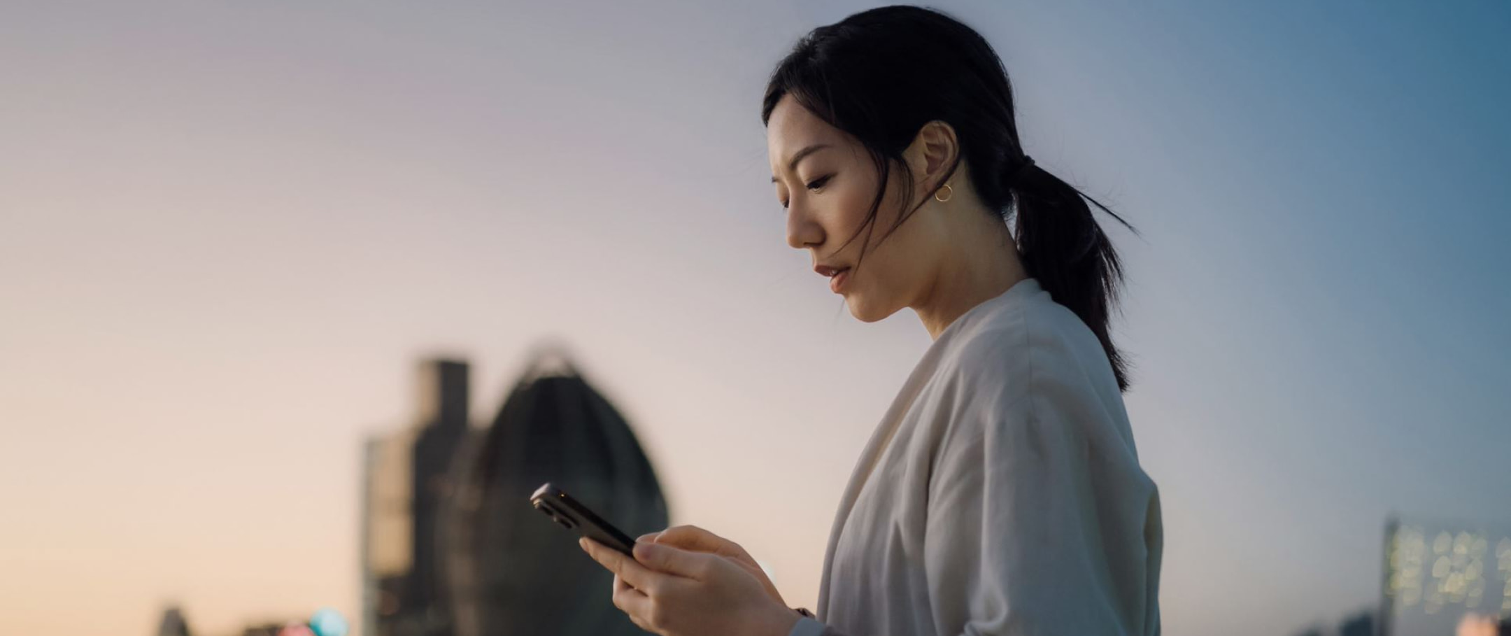 Mulher asiática de perfil segurando celular