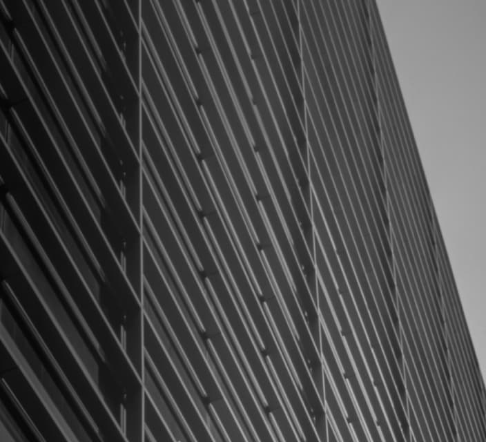 Fachada de um edifício em preto e brancoFachada da sede do C6 Bank em preto e branco, com destaque para a estrutura metálica e vidro.