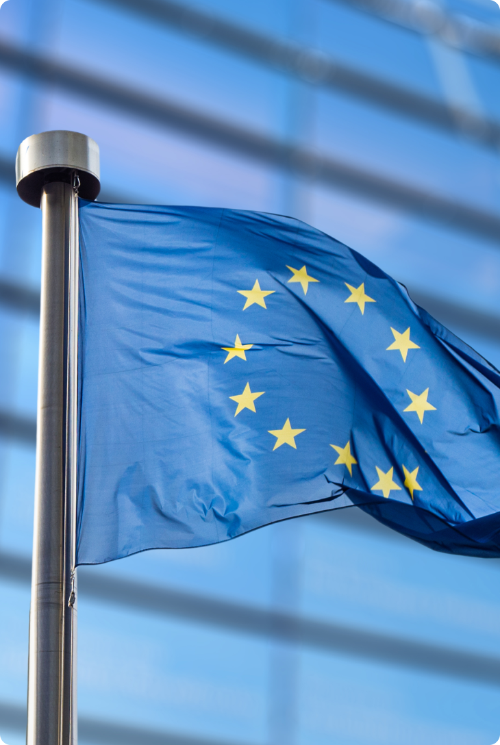 Bandeira azul da União Europeia com estrelas amarelas tremulando ao vento.