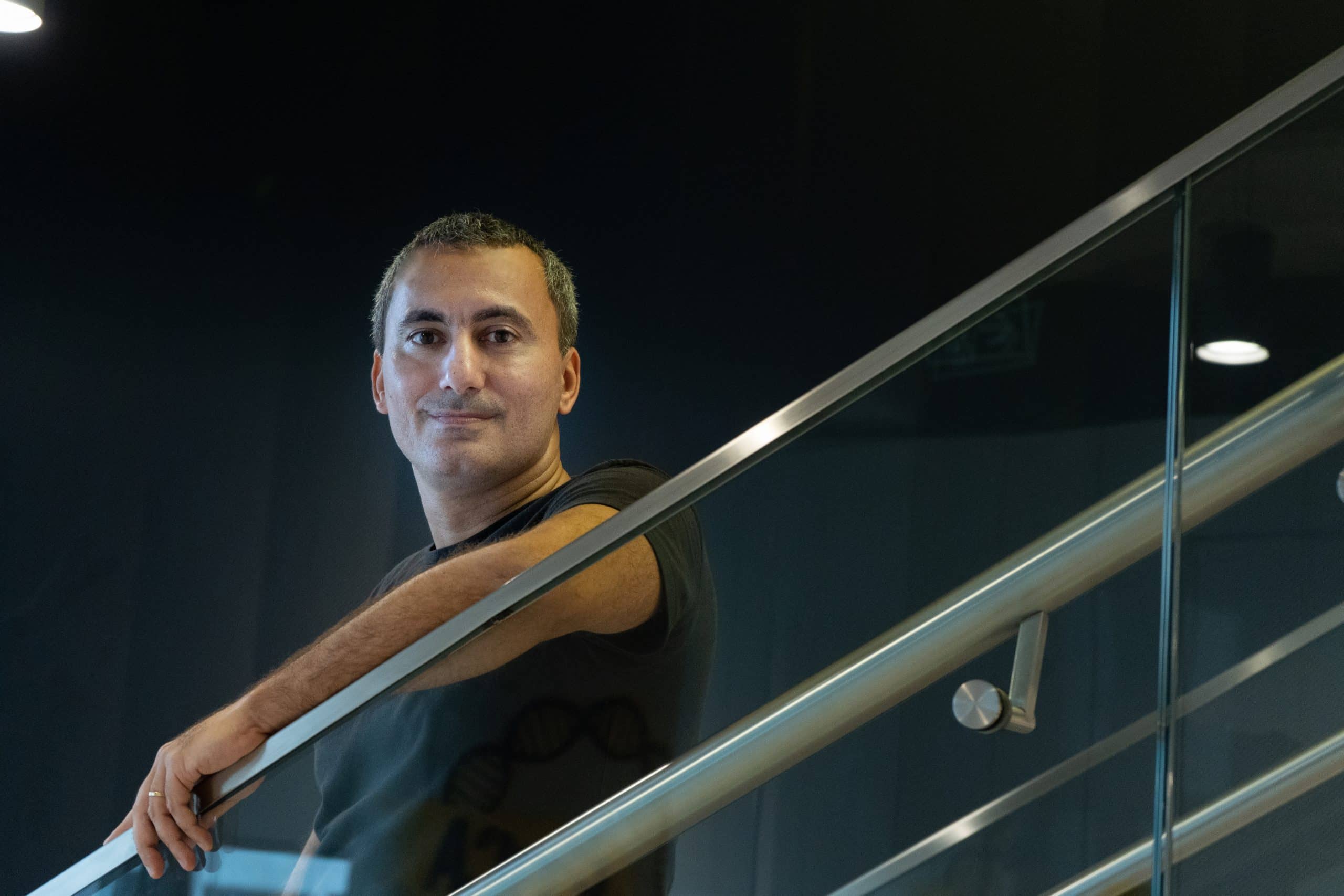 Felipe Salles, Head de Economia do C6 Bank, olhando para a câmera com meio sorriso e um dos braços apoiados no corrimão da escada.