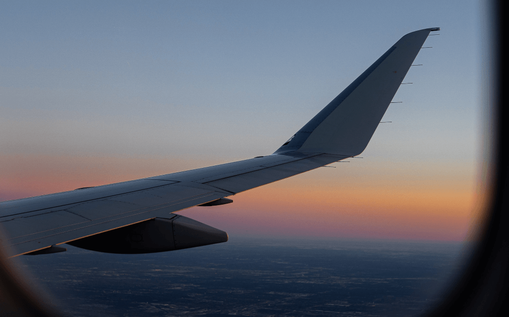 sorteio vip nível vip c6 experience - a imagem é a visão que passageiros têm quando sentam na janela de um avião, a paisagem observada consiste na asa direta do avião com um céu de fim de tarde ao fundo